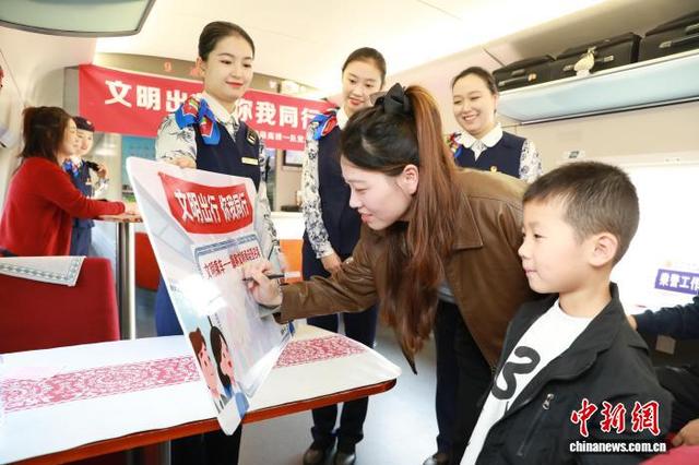 图为在南阳东站开往北京西站的G572高铁列车上，旅客在“文明承诺签署墙”上签名。任良 摄