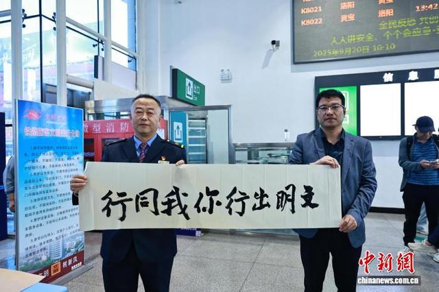 图为三门峡灵宝车站，工作人员与旅客同持文明出行书法作品合影。任伟峰 摄